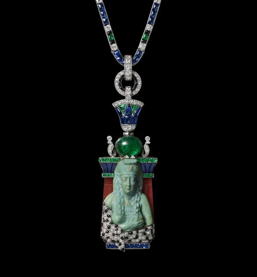 Collana Egiziana , Cartier Paris, 1927-1928, Platino, oro, maiolica egiziana blu, diamanti, zaffiri, smeraldi, corniola, turchesi, onice. La statuetta egizia blu di maiolica di Iside che allatta Horus proviene dallo stock di apprêts di Louis Cartier.. Il termine apprêts da Cartier si riferiva a uno stock di frammenti provenienti da gioielli, orologi e altri oggetti smontati, inclusi oggetti antichi di arte persiana, indiana, cinese ed egizia. Collezione CartierImages copyrights: Nils Herrmann, Collection Cartier © Cartier