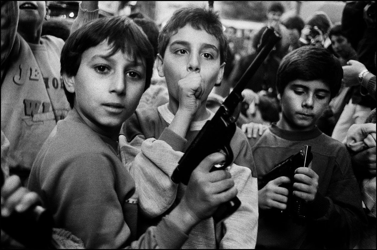 I bambini giocano con le armi che il 2 novembre, Giorno dei Morti, hanno ricevuto in dono dai genitori. Palermo, 1986© Archivio Letizia Battaglia - Solo er uso editoriale
